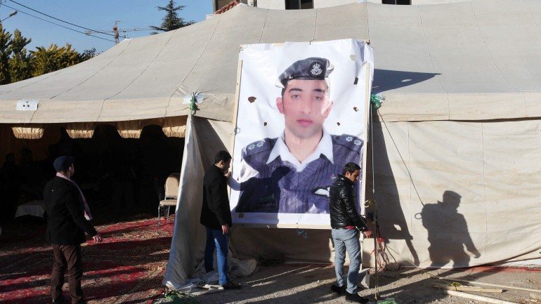 Familiares do piloto penduram uma fotografia de Muath al-Kaseasbah