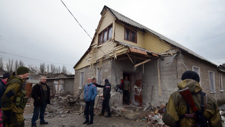 Rebeldes pró-Rússia junto de uma casa destruída nos subúrbios de Donetsk, no domingo