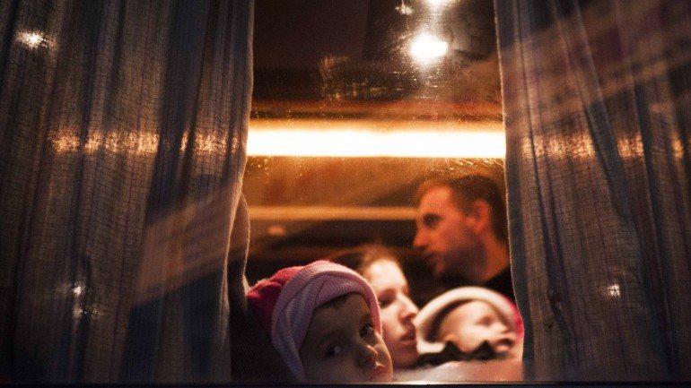 Uma família kosovar apanha um autocarro, em Pristina, com destino à Sérvia.