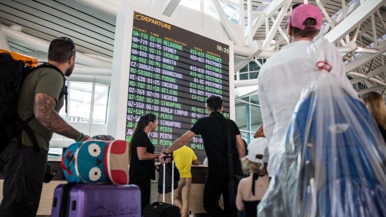Turistas estrangeiros verificam a informação de voos no aeroporto internacional de Ngurah Rai em Denpasar, Bali (na Indonesia), após o vulcão no monte Raung ter entrado em erupção