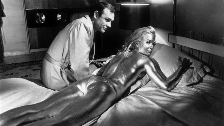 Sean Connery e a atriz inglesa Shirley Eaton, coberta de ouro, durante as filmagens de &quot;Goldfinger&quot;, realizado por Guy Hamilton.