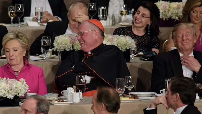 O cardeal Dolan, arcebispo de Nova Iorque, ficou sentado entre Clinton e Trump
