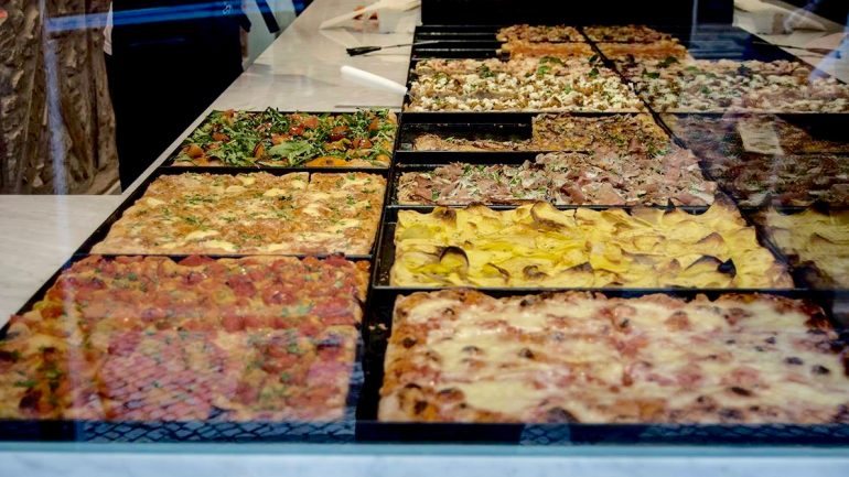 Os tabuleiros alinhados não enganam: a Romana é uma pizzaria 'al taglio' genuína.