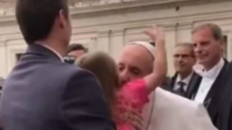 O exato momento em que a menina recebe um beijinho do Papa e joga a mão à sua cabeça