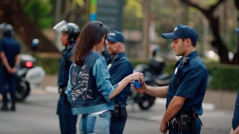 No anúncio a modelo entrega uma lata de Pepsi ao um dos polícias presentes na manifestação. A atitude está a gerar contestação