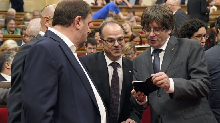 O Presidente catalão Carles Puigdemont, à direita, de telemóvel na mão