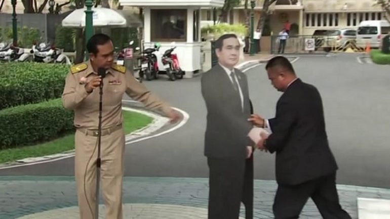 Prayuth Chan-ocha, à esquerda, a indicar ao assessor onde deve colocar o cartaz