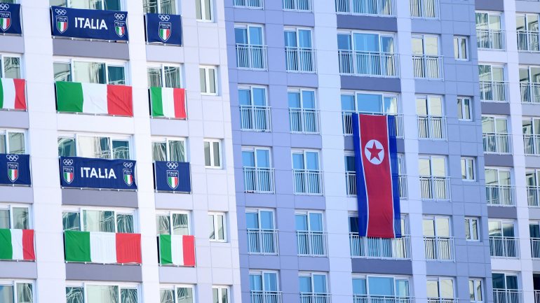 Bandeiras de Itália e da Coreia do Norte lado a lado na aldeia olímpica dos Jogos de Inverno de 2018
