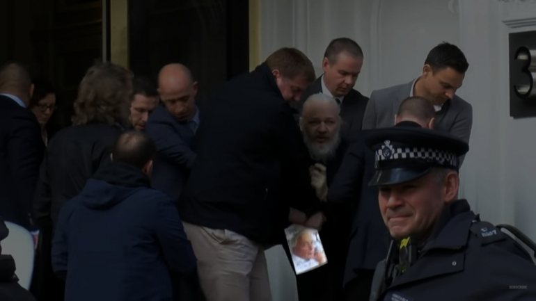 Assange fez questão de mostrar a capa do livro que trazia nas mãos ao ser detido