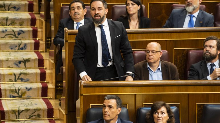O líder do Vox, Santiago Abascal, de pé. Mesmo ao seu lado está José Zaragoza. À frente, Pedro Sánchez