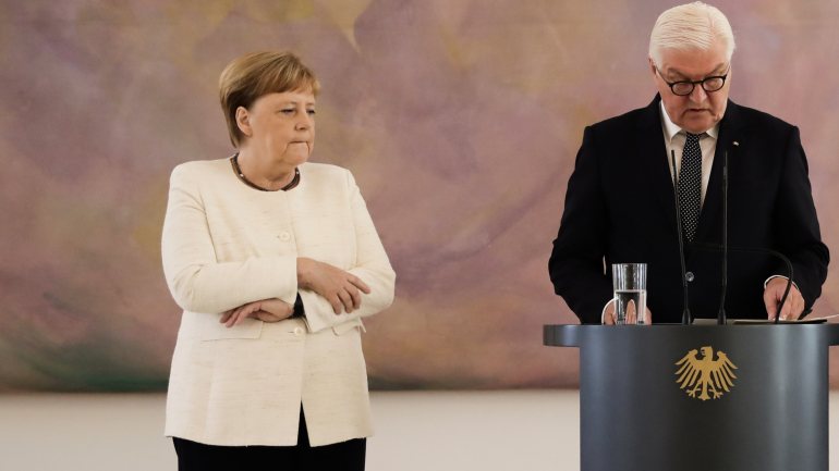 Angela Merkel tenta controlar os tremores durante uma conferência de imprensa com o presidente alemão