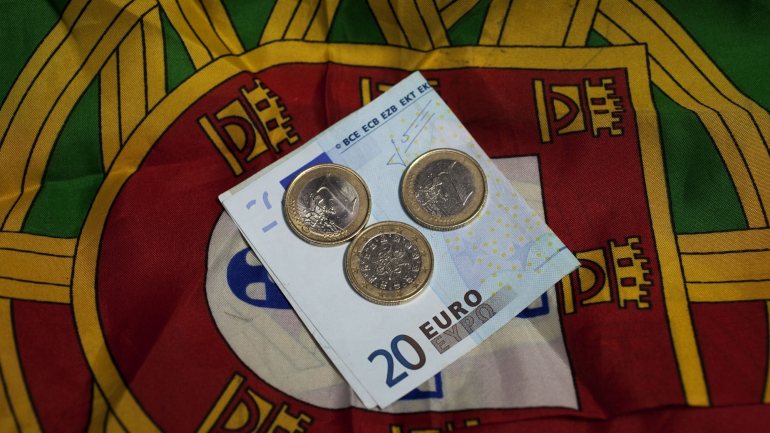 Notas e moedas de Euro sobre a bandeira de Portugal