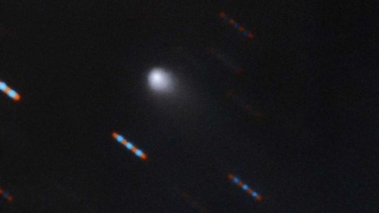 Os pontos arrastados vermelhos e azuis são as estrelas próximas ao cometa, que parecem arrastadas por causa da longa exposição