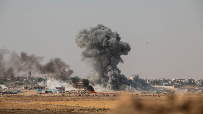 Uma fotografia tirada do território turco mostra o fumo a subir de alvos dentro da Síria durante bombardeamentos pelas forças turcas na cidade de Ras al-Ein a 13 de outubro de 2019