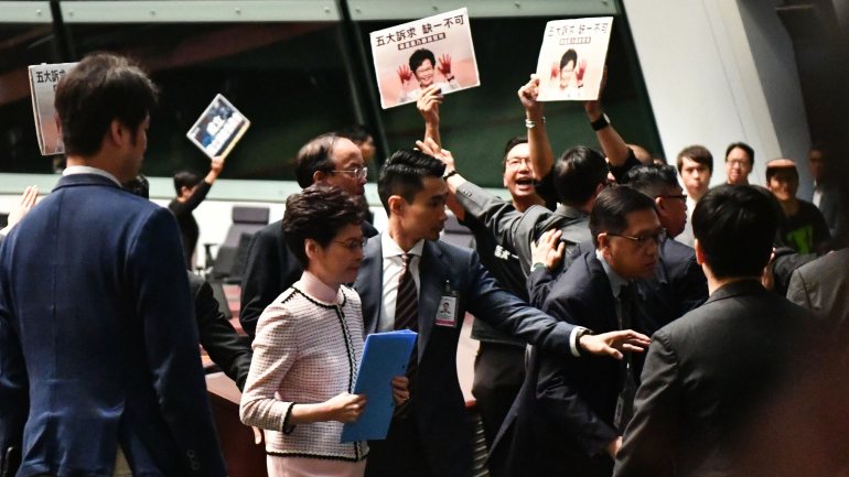 Carrie Lam a ser escoltada para sair da Assembleia, rodeada por deputados que se manifestam
