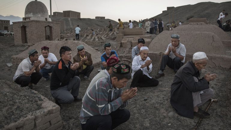 Homens muçulmanos da etnia Uyghir a rezar, na região de Xinjiang