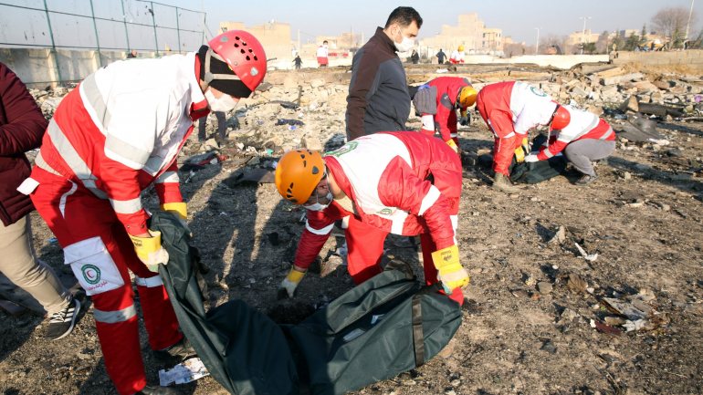 Membros do Crescente Vermelho Internacional recolhem corpos de vítimas no meio dos destroços, depois da queda do Boeing 737-800 da Ukraine International Airlines