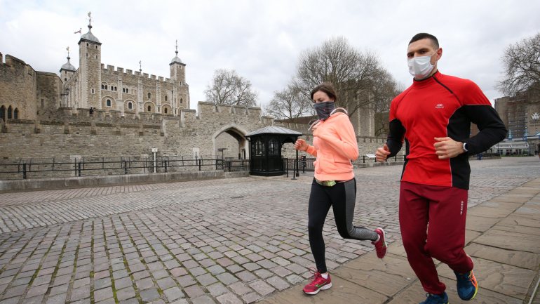 Uma mulher e um homem correm junto à Torre de Londres, no Reino Unido