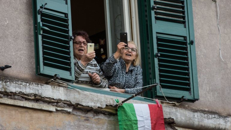Duas mulheres assistem a uma iniciativa de solidariedade nas ruas de Roma enquanto cumprem o isolamento obrigatório