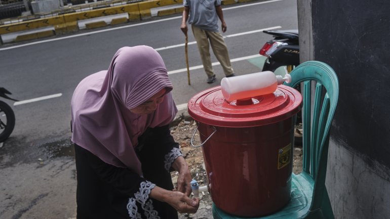 Uma mulher lava as mãos num sistema improvisado num bairro de Jacarta