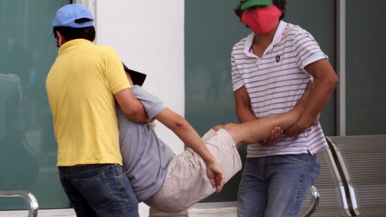 Dois homens transportam um terceiro, doente, para um hospital em Guayaquil