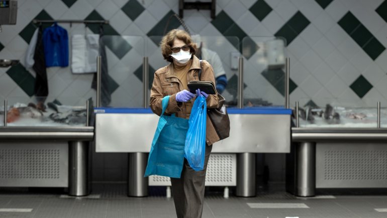 Uma mulher protegida com máscara e luvas faz compras no Mercado da Graça