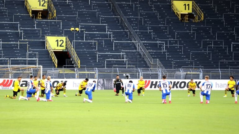 Jogadores do B. Dortmund e do Hertha Berlim ajoelharam-se durante o minuto de silêncio cumprido antes do início do jogo