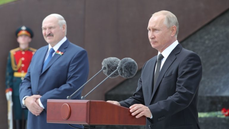 Vladimir Putin (dir.) discursa ao lado de Alexander Lukashenko (esq.)