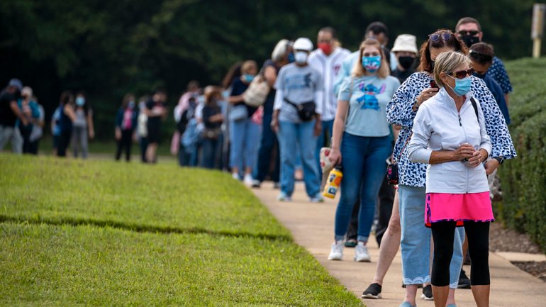 Os eleitores na Virgínia aguardam na fila para votar nas eleições presidenciais, com distanciamento físico e máscaras