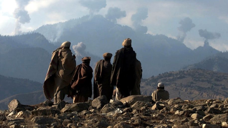 Combatentes afegãos anti-talibã observam bombardeamento à distância
