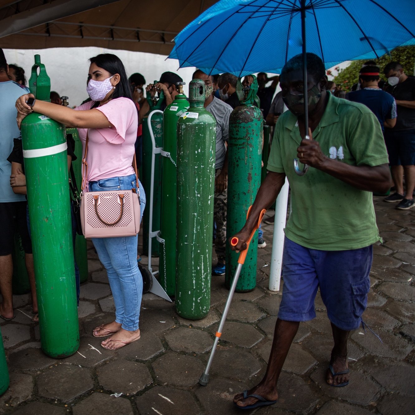 epa08949847 Relatives of patients infected with Covid-19 wait for hours since early in the morning to refill their oxygen cylinders at the Carboxi company, in Manaus, Amazonas, Brazil, on 19 January 2021. An air, river and terrestrial fleet began on 19 January the distribution of vaccines against covid in the collapsed Brazilian state of Amazonas, vaccines that will have to reach the most distant villages, a tremendous task due to the difficulties imposed by the largest jungle on the planet.  EPA/RAPHAEL ALVES