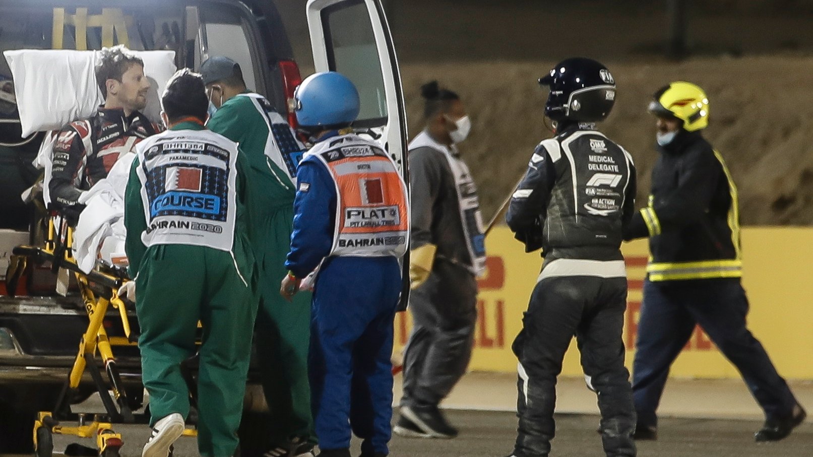 epa08851028 French Formula One driver Romain Grosjean (L) of the Haas F1 Team receives medical assistance after a crash during the start of the Formula One Grand of Bahrain on the Bahrain International Circuit in Sakhir, Bahrain 29 November 2020.  EPA/Hamad I Mohamed / Pool