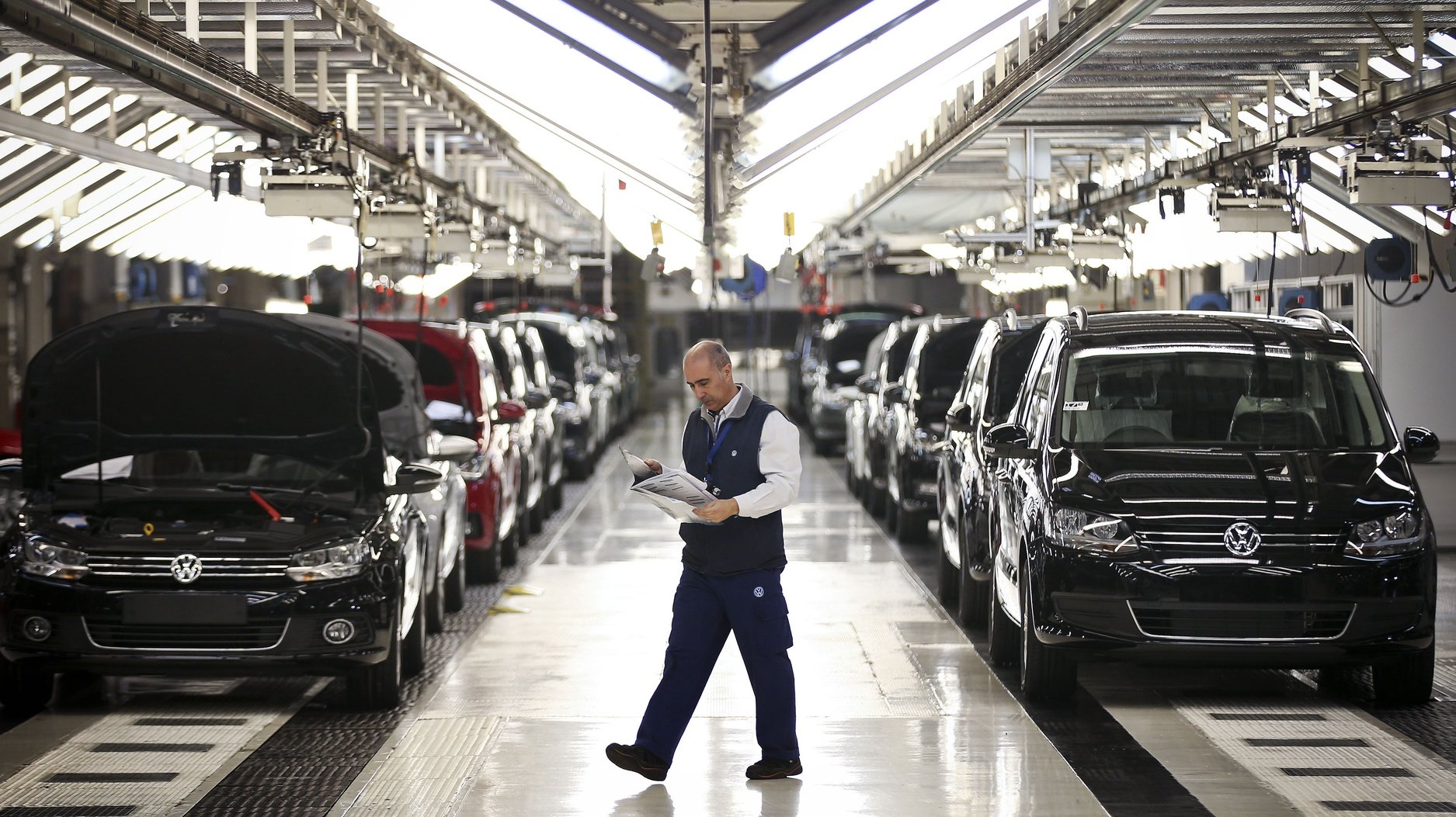 Um trabalhador da fábrica Autoeuropa do grupo alemão Volkswagen passa pela linha de sáida de veículos produzidos numa altura em que se celebram os 20 anos do início da produção da Autoeuropa em Portugal, em Palmela, concelho de Setúbal, 26 de abril de 2015. (ACOMPANHA TEXTO) MÁRIO CRUZ/LUSA