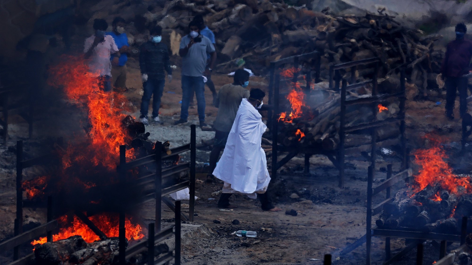 epaselect epa09209124 Funeral pyres for COVID-19 victims burn during a mass funeral at a makeshift cremation ground at Giddenahalli in the outskirts of Bangalore, India, 18 May 2021. India surpassed 25 million cases of the coronavirus on 18 May since the start of the pandemic, despite a decline in infections in recent days, while also recording a new daily record of 4,329 deaths. The country registered 263,533 infections in the last 24 hours, according to data from the Indian Ministry of Health, the lowest number in a month after India reported a record of over 400,000 cases everyday two weeks ago. The total Covid-19 toll now stands at 25.2 million cases - second highest after the United States - and 278,719 deaths - third highest after the US and Brazil.  EPA/JAGADEESH NV
