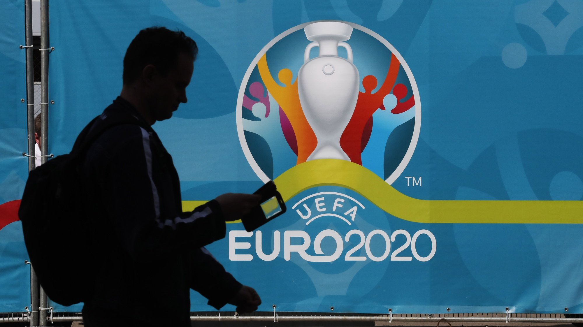 epa09251609 A man walks past a poster with the UEFA EURO 2020 logo ahead of the UEFA EURO 2020 soccer tournament in St.Petersburg, Russia, 06 June 2021. The European Championship, which was delayed from last year due to the Coronavirus pandemic features seven matches in St. Petersburg.  EPA/ANATOLY MALTSEV