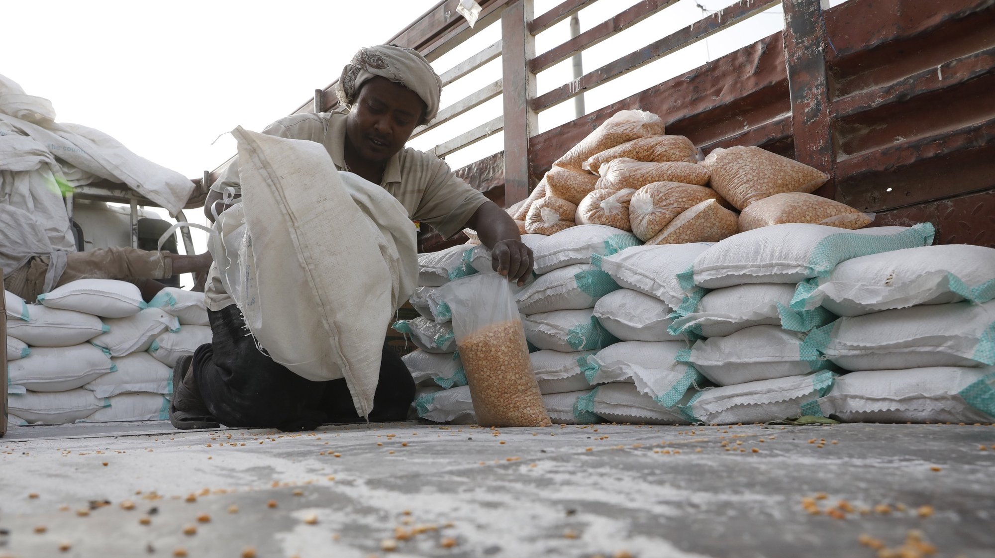 epa09751617 An aid worker prepares bags of beans during a food aid distribution amid a severe food insecurity, at al-Jarahi town, in the port province of Hodeidah, Yemen, 10 February 2022 (Issued 13 February 2022). The United Nations has reported that the humanitarian response plan for Yemen for 2021 received only 58 percent of the funding requirements, with a deficit of about 1.6 billion US dollar, as some 24 million people, out of the war-ridden country&#039;s 30 million population, are urgently in need of protection and humanitarian assistance, including over five million people are on the brink of famine. Aid agencies suspended vital relief programs in impoverished Yemen as of January 2022 due to severe funding shortfalls. Yemen has been mired in a war since the Houthis ousted the internationally recognised government from the capital Sana&#039;a in late 2014, leaving millions suffering from food and medical shortages. The conflict escalated when the Saudi-UAE led coalition intervened to back the government forces in March 2015.  EPA/YAHYA ARHAB
