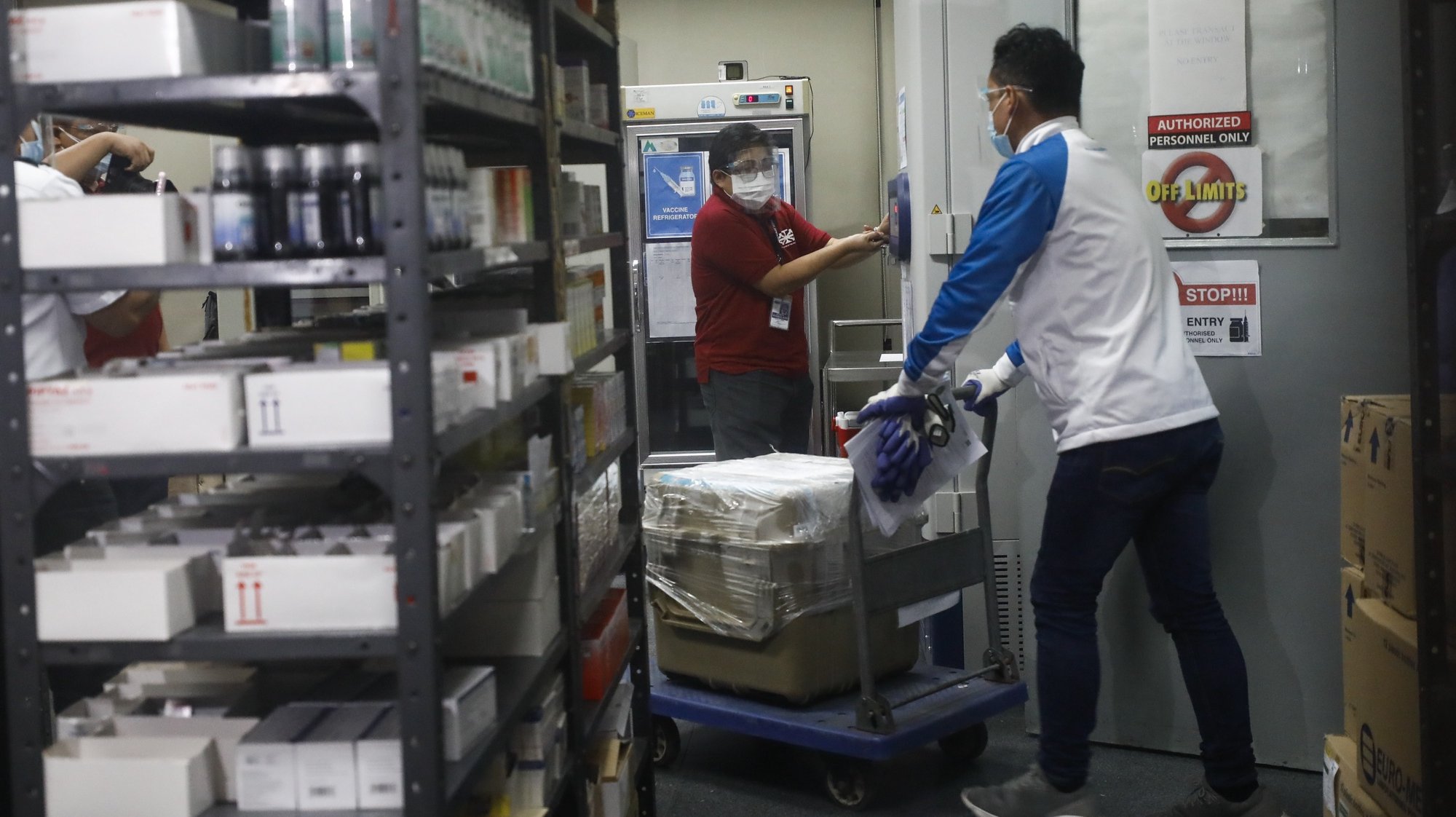 epa08998093 A worker (R) delivering a mock batch of COVID-19 vaccine enters a pharmacy during a vaccine delivery drill at the Lung Center of the Philippines medical facility in Quezon City, Metro Manila, Philippines, 09 February 2020. The Philippines health department supervised the delivery and vaccination drill to ensure the vaccine is properly handled once available in the country.  EPA/ROLEX DELA PENA