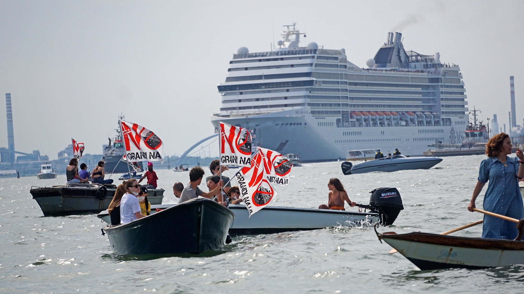 epa09249793 Activists of the committee &#039;No Grandi Navi&#039; (No big ships), headed for the MSC Orchestra on board of small boats and waving flags, protest against the cruise ship being allowed in the Lagoon, during the navigation of the ocean-going liner in the Channel of the Giudecca, Venice, Italy, 05 June 2021.  EPA/Andrea Merola