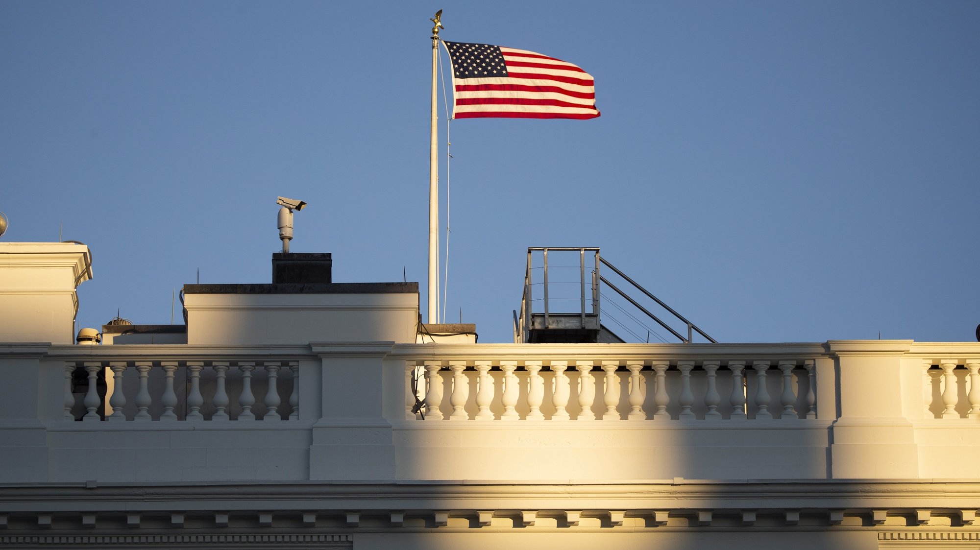 epa08961349 The US national flag is seen above the White House before sunset in Washington, DC, USA, 23 January 2021.  EPA/MICHAEL REYNOLDS / POOL