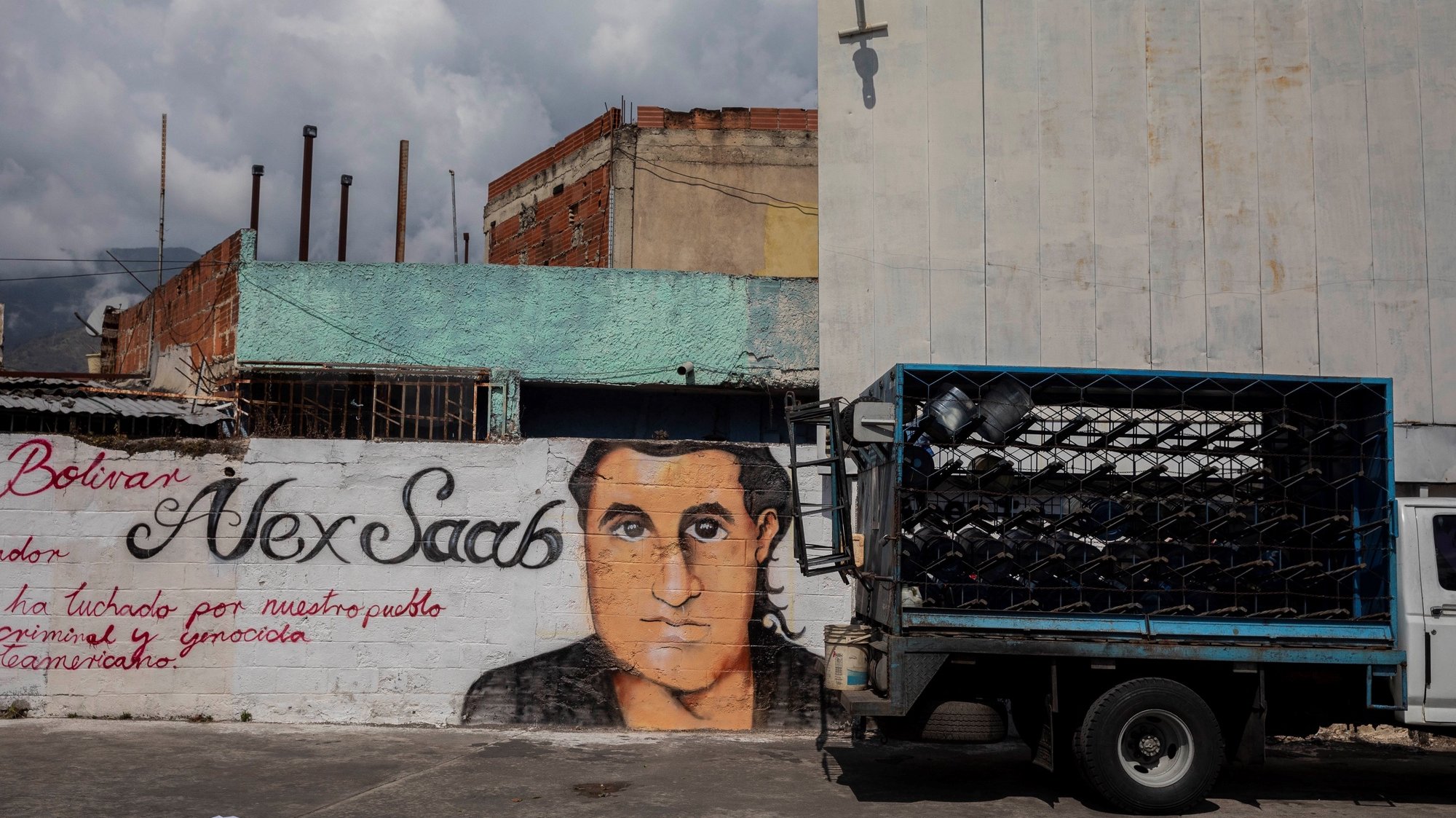 epa09030459 A small truck passes by a graffiti with the image of Alex Saab&#039;s face in Caracas, Venezuela, 22 February 2021. Chavista supporters have painted murals in the Venezuelan capital to show their support and request the release of Alex Saab, a Colombian businessman detained in Cape Verde and whom the United States is asking for extradition by accusing him of being a front man for the president of Venezuela, Nicolas Maduro.  EPA/Rayner Pena