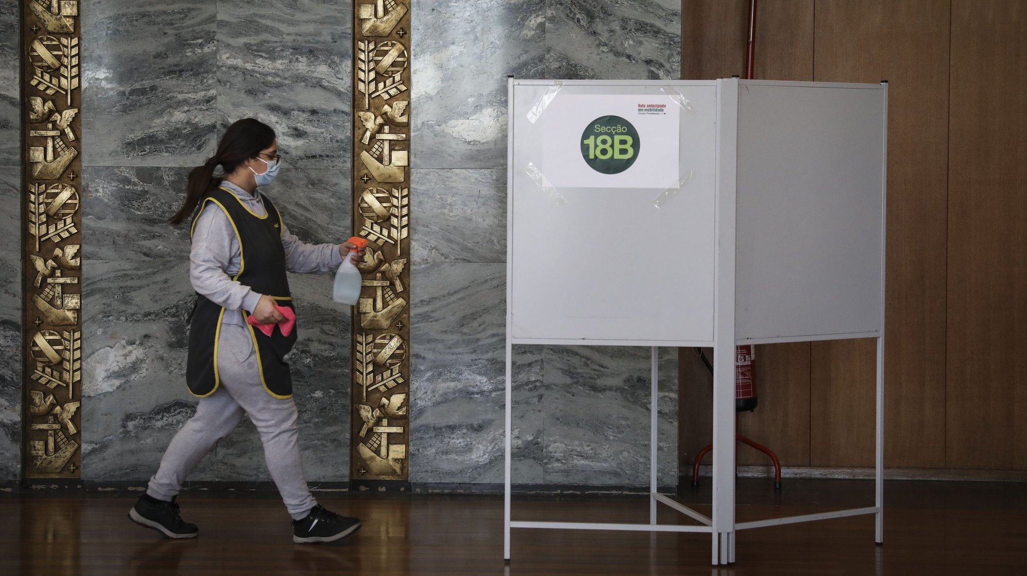 Uma funcionaria da limpeza momentos andes de desinfetar a urna, no dia de voto antecipado nas Eleições Presidenciais de 2021, na Cidade Universitária, em Lisboa, 17 de Janeiro de 2021. RODRIGO ANTUNES/LUSA