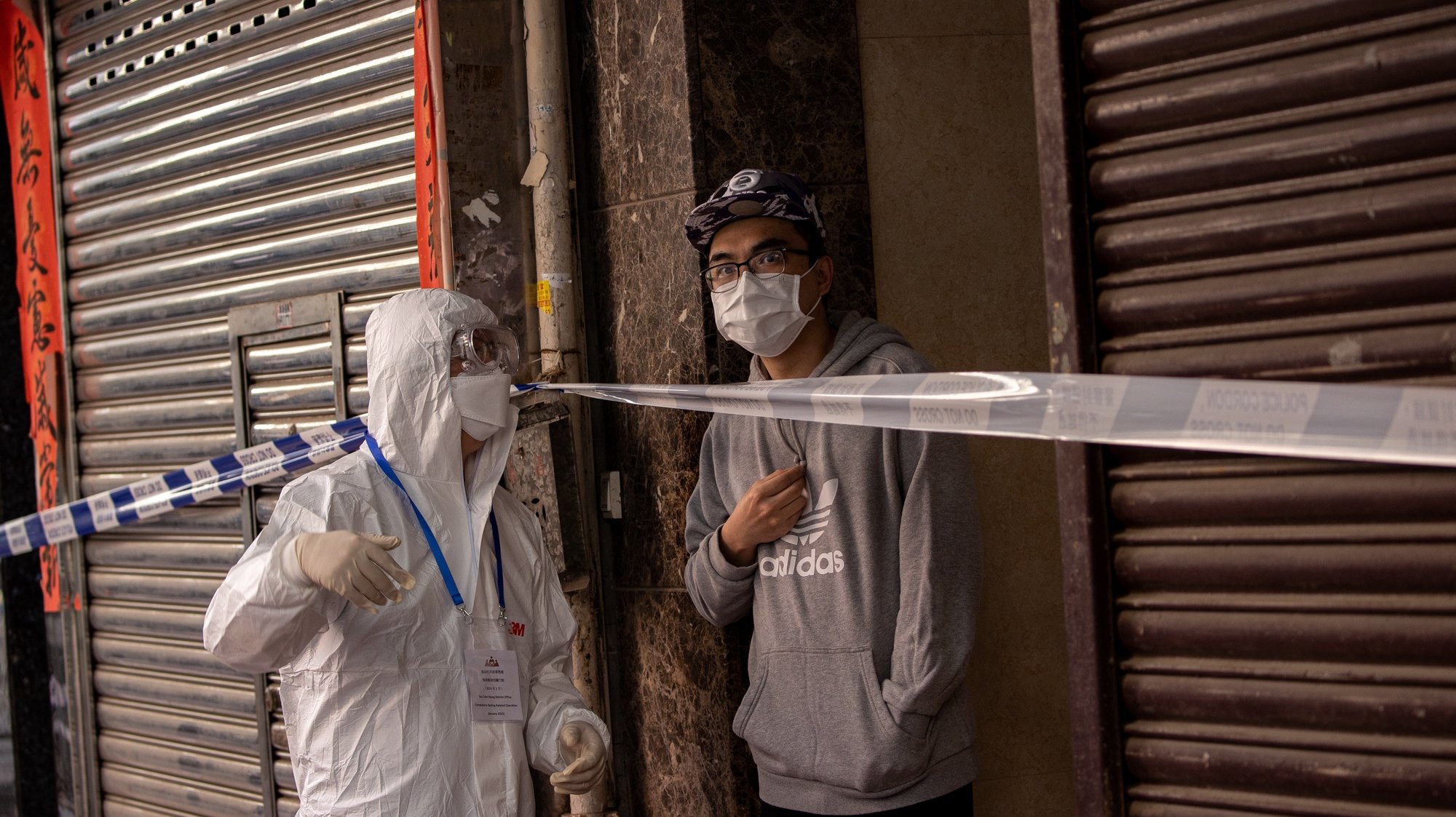 epa08959120 A local resident is forbidden to leave his building by a civil servant in face mask and protective gown during a lockdown in Jordan, Hong Kong, China, 23 January 2021. The Hong Kong government placed around 10,000 residents in an estimated 200 buildings of Jordan district under a 48-hours COVID-19 lockdown. People will not be allowed to leave until most of the testing for COVID-19 has been completed and they have a negative result.  EPA/JEROME FAVRE