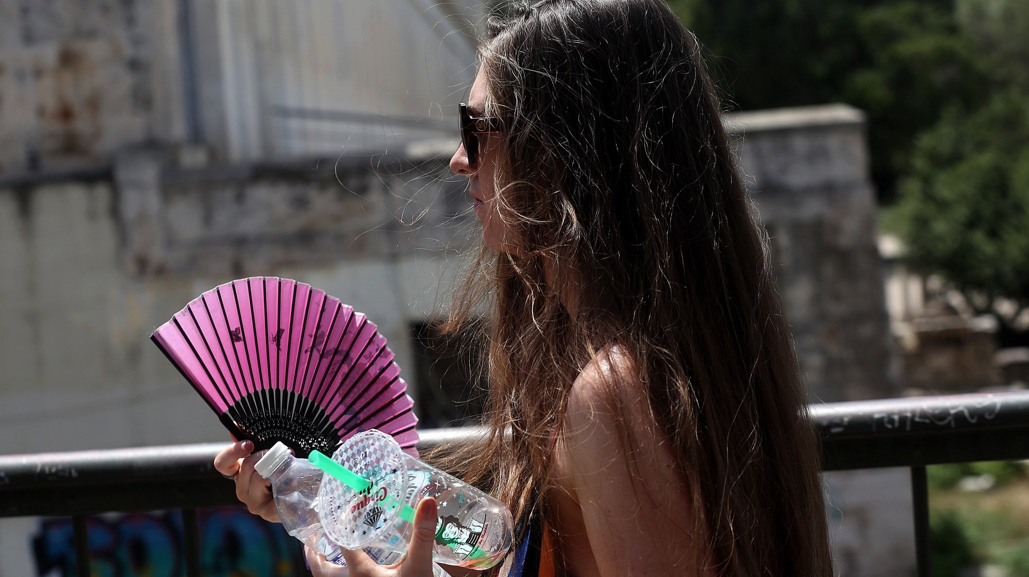 epa09387958 A woman uses a hand fan during a heatwave, in Athens, Greece, 02 August 2021. The long and blisteringly hot heatwave in Greece is expected to peak in the current week, as hot air masses moving up from Africa send temperatures soaring. Maximum temperatures will reach 43-45C on average and rise as high as 46-47C in some localities, while the risk of fires is exceptionally high.  EPA/ORESTIS PANAGIOTOU