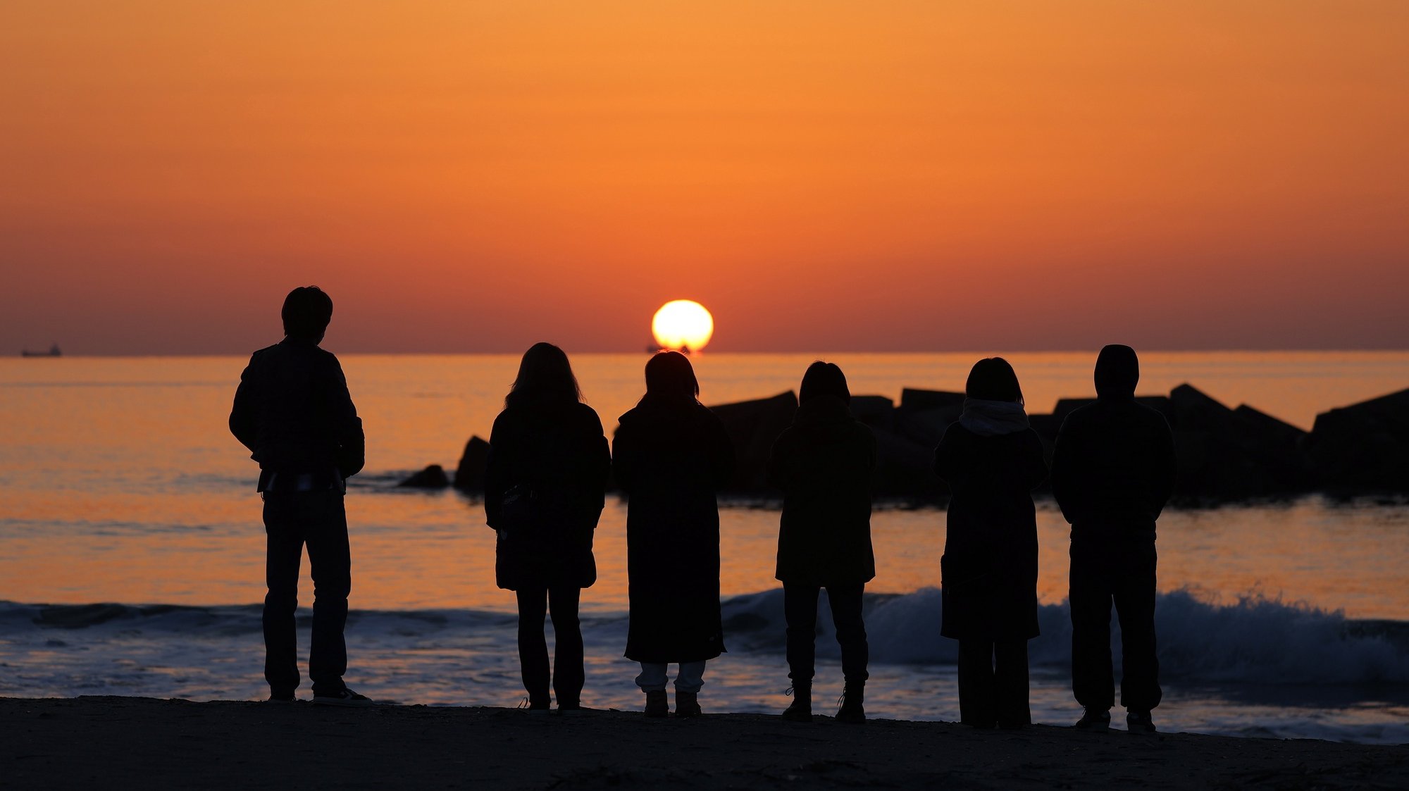 epa09066731 Local residents stand on the seashore at sunrise in Arahama, Miyagi prefecture, northeastern Japan, early 11 March 2021. Japan is commemorating the 10th anniversary of the Great East Japan Earthquake and subsequent tsunami in which approximately 20,000 people lost their lives on 11 March 2011.  EPA/JIJI PRESS JAPAN OUT EDITORIAL USE ONLY/  NO ARCHIVES