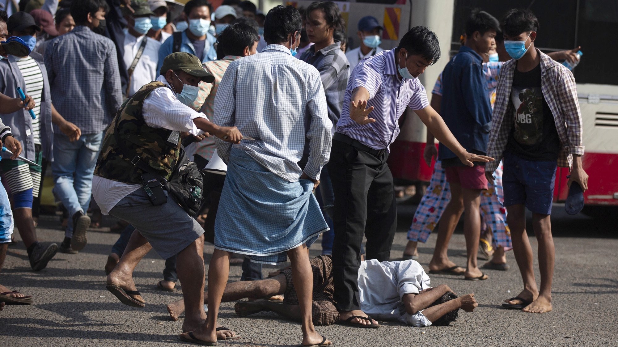 epa09035142 A resident falls to the ground as pro-military supporters attack residents with sling shots and projectiles near the central railway station in Yangon, Myanmar, 25 February 2021. Residents were banging pots and pans before they were attacked by pro-military supporters. Anti-coup demonstrations continued amid regional diplomatic attempts to reach a resolution to weeks of unrest caused by the military coup.  EPA/STR