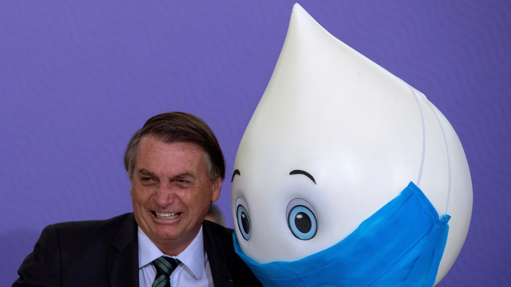 epa08887785 Brazilian President Jair Bolsonaro poses for photos with the mascot Ze Gotinha, a traditional character in Brazil created to raise awareness about vaccines, during the launch of the National Vaccination Plan against covid-19, at the Planalto Palace in Brasilia, Brazil, 16 December 2020. The Brazilian Government presented the master lines of its future vaccination plan against covid-19, which plans to immunize 210 million inhabitants in about 16 months, but has not yet set a start date for the process. According to the Ministry of Health, to establish the day on which the first of the five planned vaccination phases will begin, one must wait for an antidote to be approved and registered by the National Health Surveillance Agency (Anvisa), which could occur for next February.  EPA/Joedson Alves