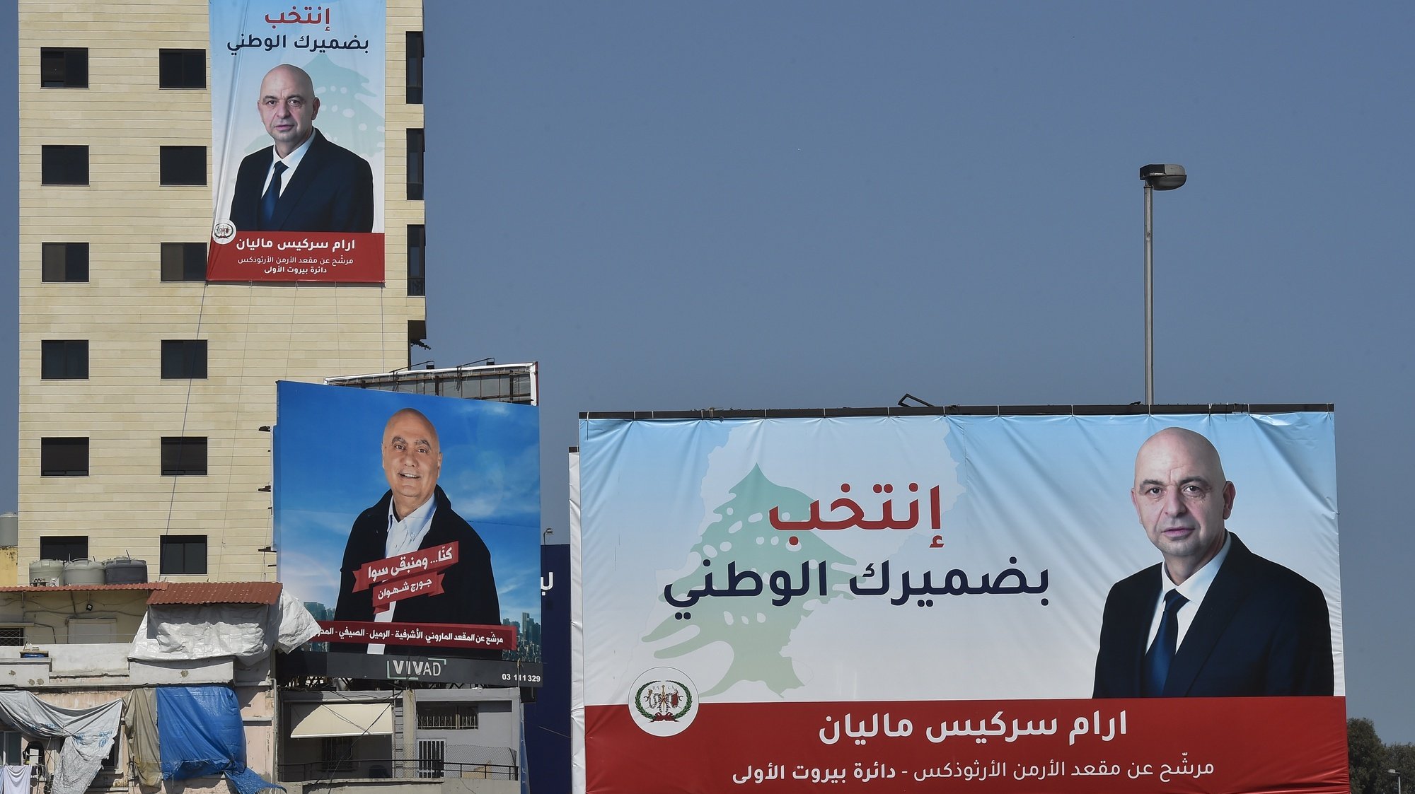 epa09939370 A large pre-election poster of the Lebanese candidates for the parliamentary elections displays in Beirut, Lebanon, 11 May 2022. Despite the campaigns for electoral equality launched by international organizations, huge posters of male candidates dominate facades and billboards in Beirut avenues, while the few and small posters in search of votes for women, 155 of a total of 1,043 applicants, hide under walkways and blind spots. Lebanese parliamentary elections in Lebanon are scheduled for 15 May 2022.  EPA/WAEL HAMZEH