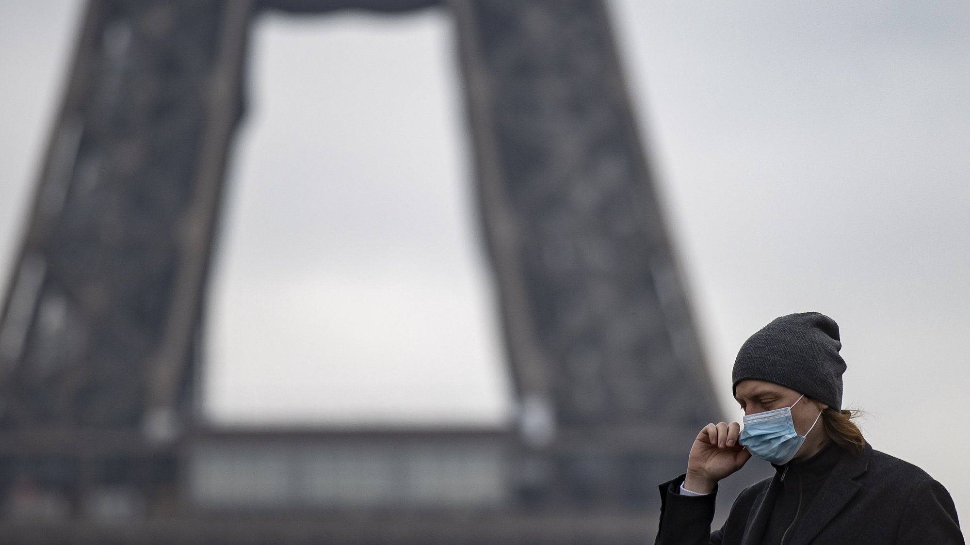 Uma mulher utiliza máscara facial perto da Torre Eiffel, em Paris, França