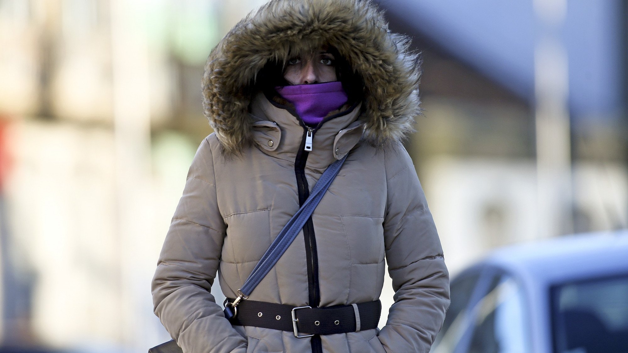 Uma mulher protege-se do frio que se faz sentir no Porto