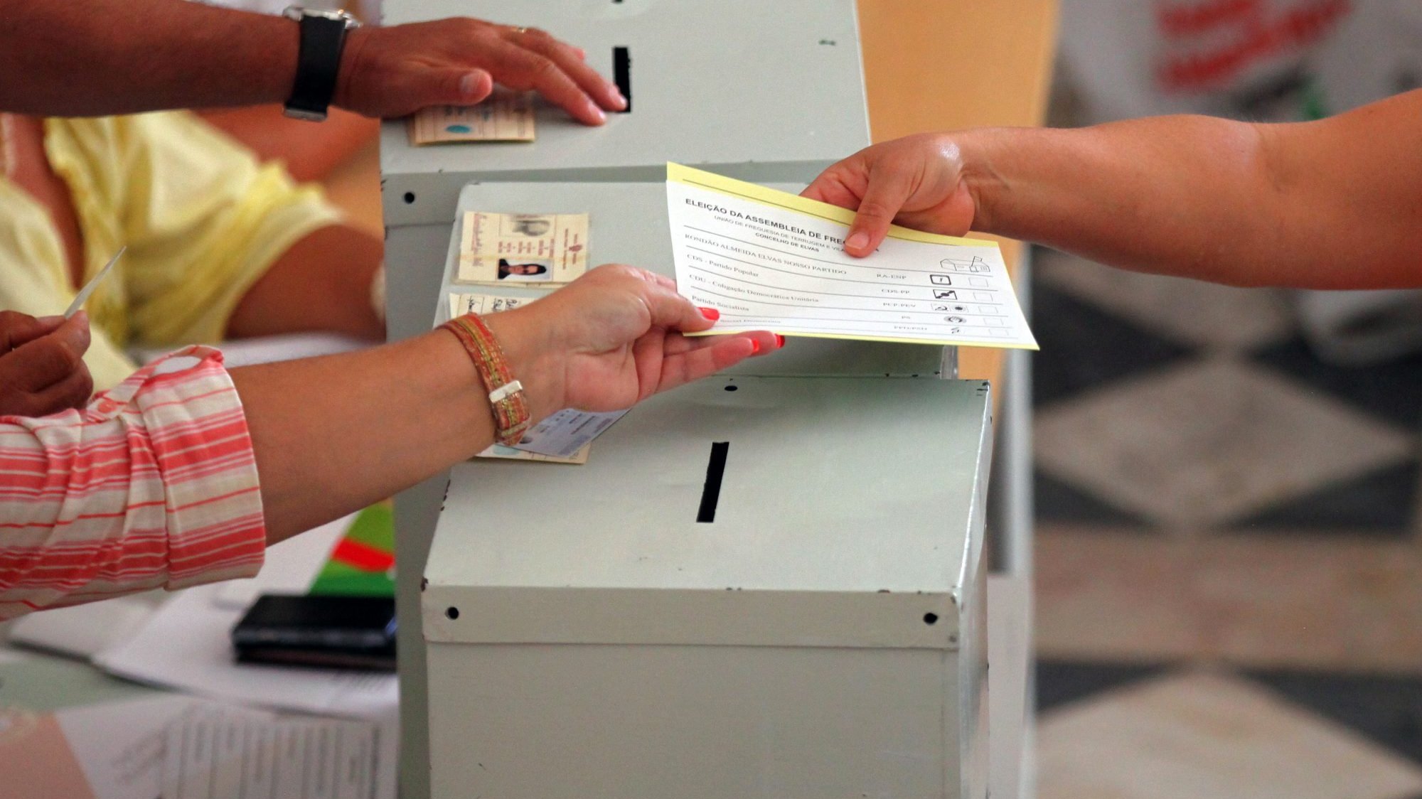 Uma eleitora recolhe os boletins de voto para cumprir o seu direito cívico numa mesa de voto